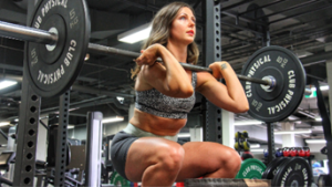 Woman performing a barbell squat in gym.